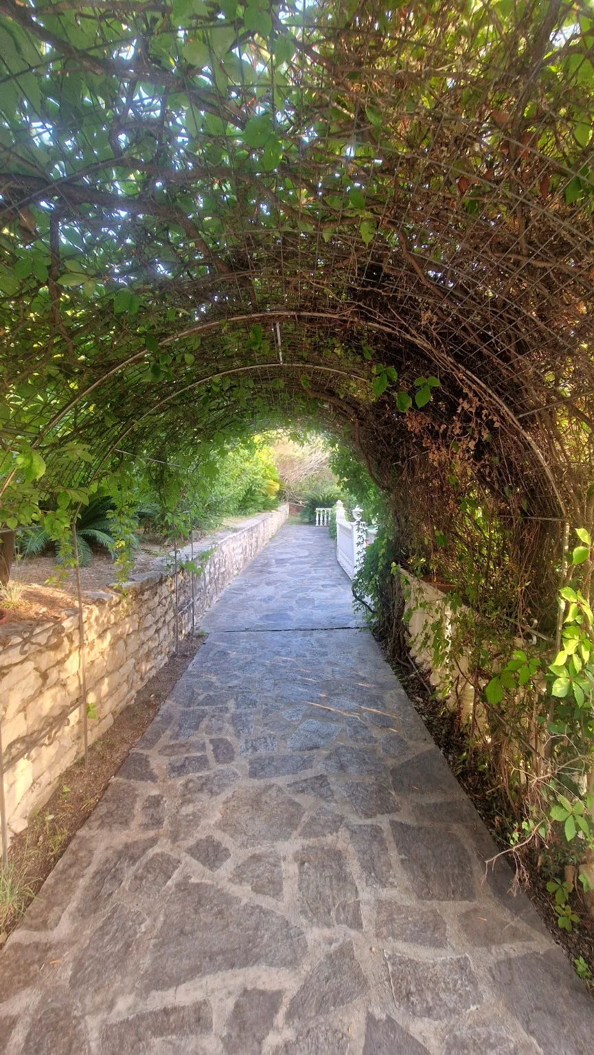 Green garden arch and stone pathway at Villa Vanda in Lygia
