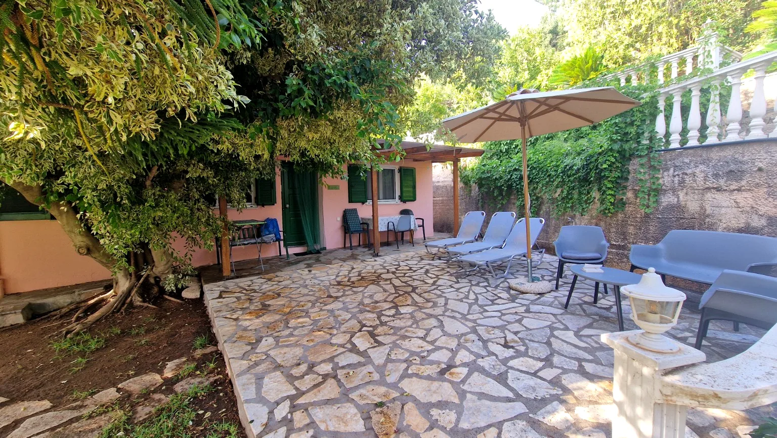 Private stone terrace with sun loungers and shaded seating at Il Prato, Villa Vanda
